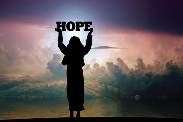 Silhouette of woman holding the word HOPE against a sunrise